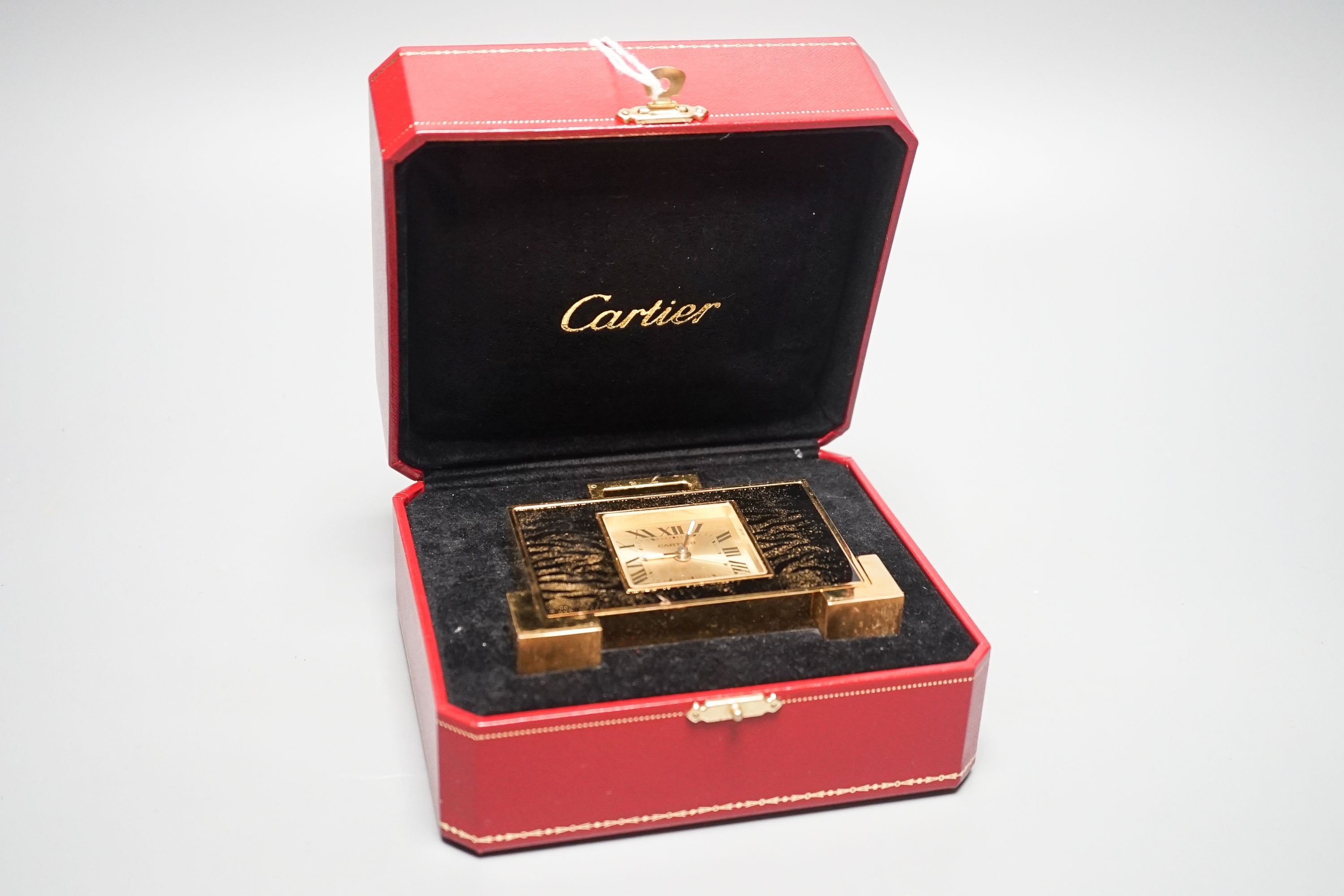 A cased Cartier gilt metal travelling clock, 10.5 cm wide, with certificate booklet